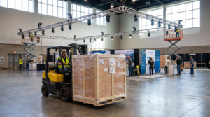 Forklift moving an exhibit crate across a convention center hall, illustrating trade show shipping costs and drayage